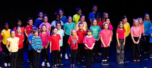 Students in brightly coloured t-shirts  performing in Got to Sing event
