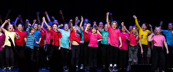 Students in brightly coloured t-shirts  performing in Got to Sing event
