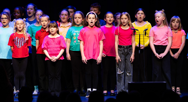 Students in brightly coloured t-shirts  performing in Got to Sing event