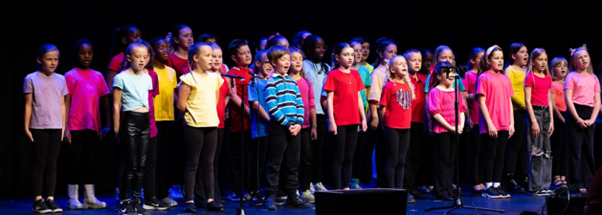 Students in brightly coloured t-shirts  performing in Got to Sing event