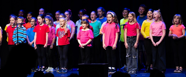 Students in brightly coloured t-shirts  performing in Got to Sing event